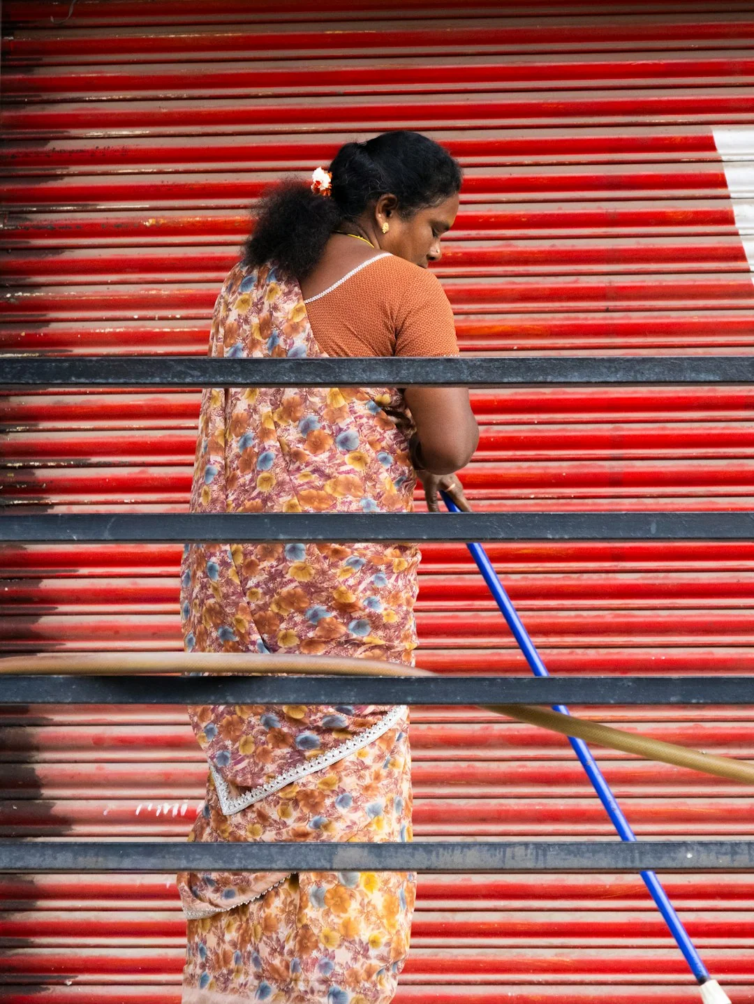 our-story Agent d’entretien vêtu d’un uniforme orange vif, balayant le trottoir près d’un bus public en milieu urbain.